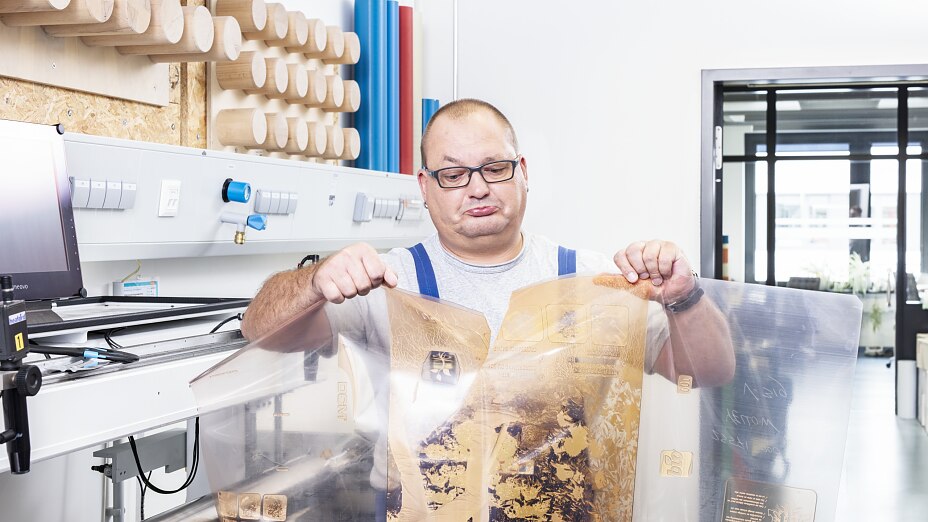 Mitarbeiter betrachtet beschädigte Flexo-Druckplatte Mitarbeiter betrachtet beschädigte Flexo-Druckplatte