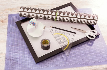 Das brauchen wir:
Einfacher Bilderrahmen mit Acrylglas in gewünschter Größe, Geschenkpapier in Schwarz-Weiß, Geodreieck, Schere, Bleistift, tesa extra Power® ECO REPAIR, 5 m x 38 mm, schwarz, tesafilm® Tischabroller Compact