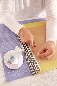 Die Rahmenrückwand mittig auf die Rückseite des Papiers legen und die Längskanten 5 cm umknicken. Mit tesafilm® fixieren.