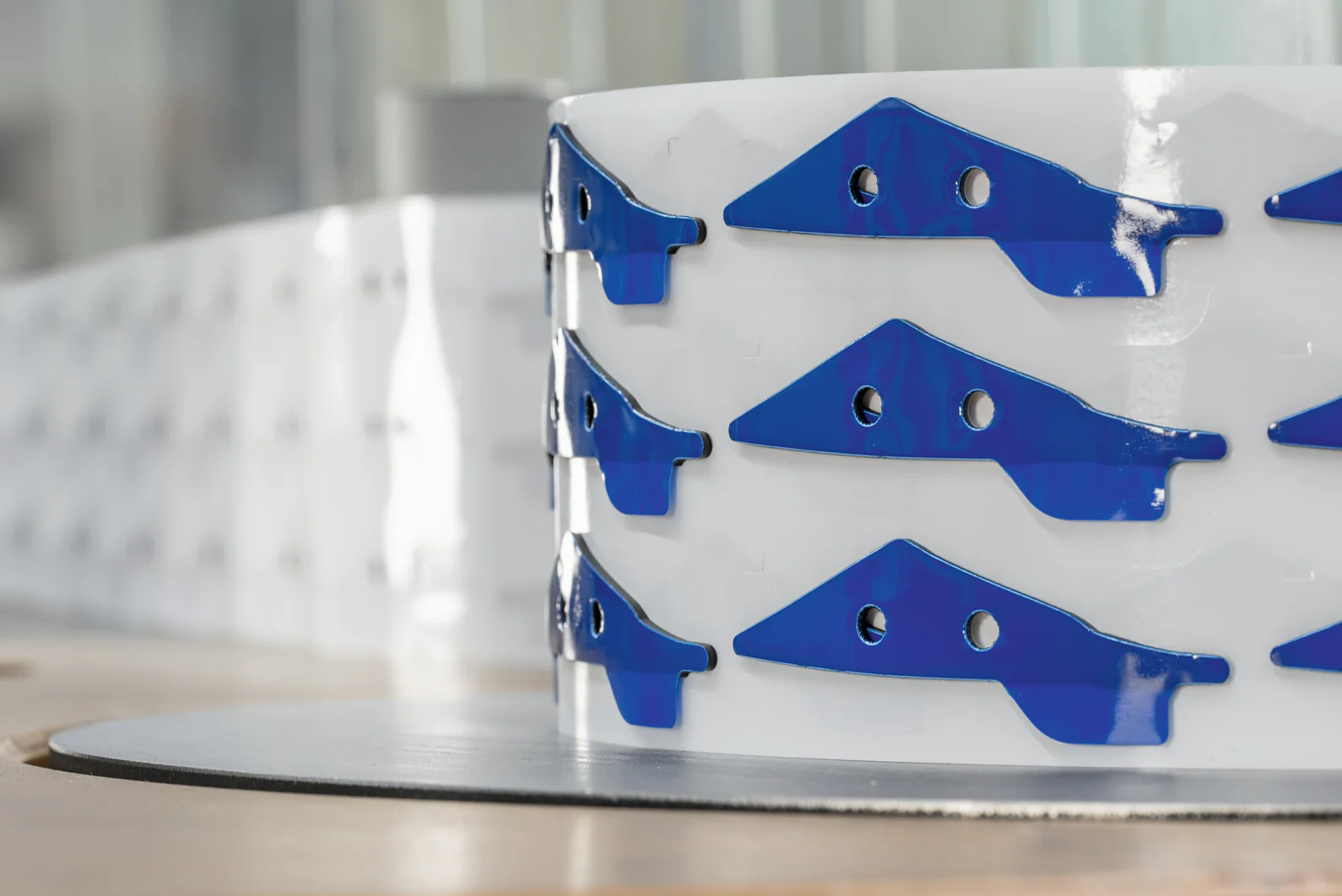 Nahaufnahme einer weiß-blauen dekorativen Struktur mit einem sich wiederholenden Muster aus blauen geometrischen Formen und Löchern, sanft beleuchtet. Das Objekt steht auf einer abgerundeten Basis vor einem hellen, unscharfen Hintergrund. (This text has been generated by AI)