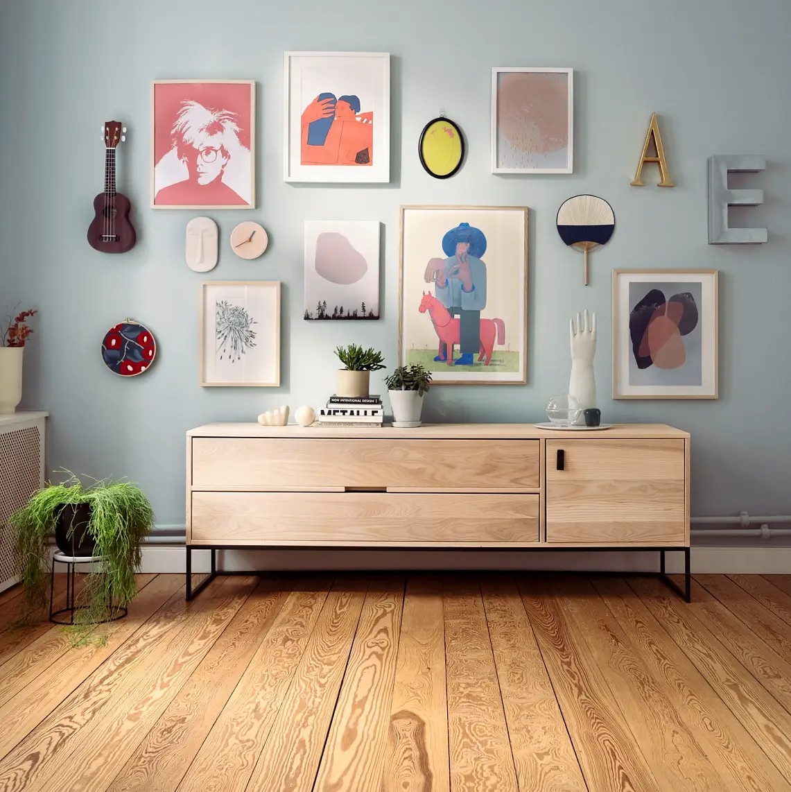 Wall Gallery – Teaser: Bilder, Buchstaben, Geige und Deko-Elemente hängen an heller Zimmerwand.