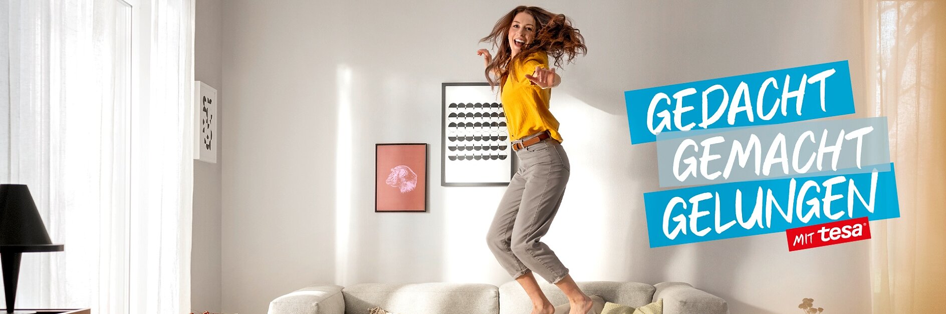 Wohnzimmerideen Header: Frau springt glücklich lachend auf dem Sofa
