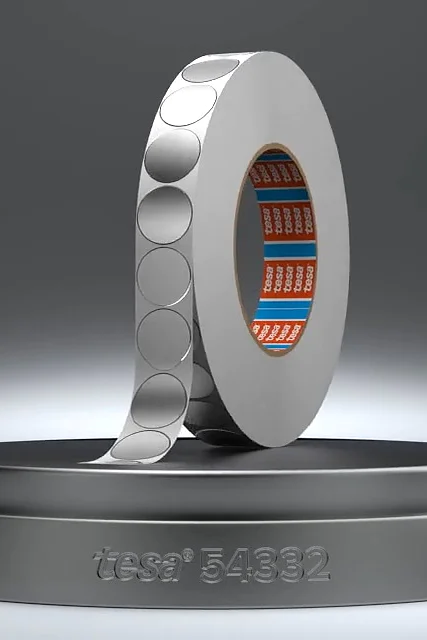 Ein Metallring mit gemusterter Oberfläche steht vertikal auf einem runden Sockel. Der innere Teil des Rings ist blau und orange gestaltet. In den Sockel ist der Text „itseez3 5892“ eingraviert. Der Hintergrund ist ein Farbverlauf aus Grautönen. (This text has been generated by AI)