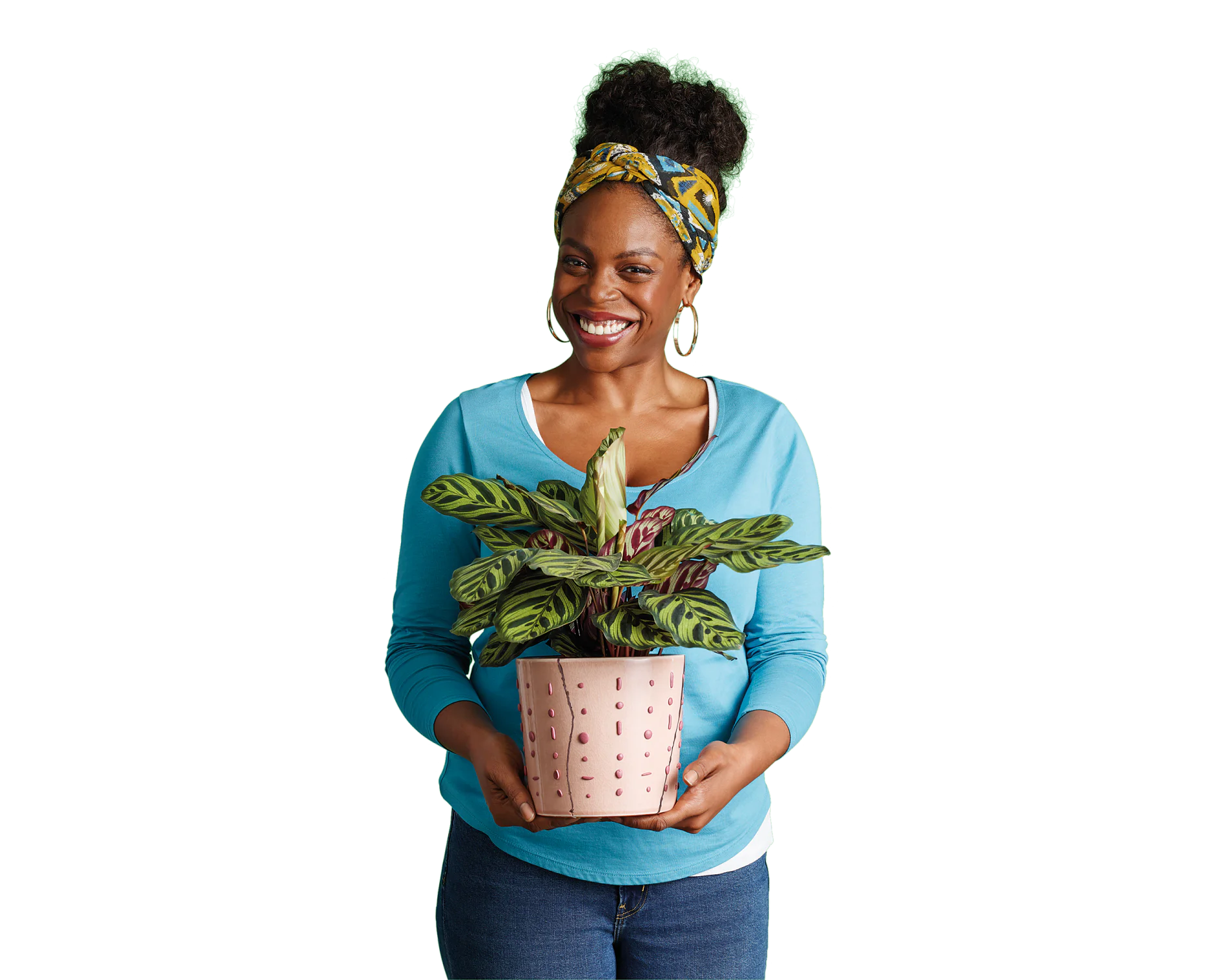 Ebella-posing-with-plant-CMYK Eine Person in einem blauen Pullover und Jeans hält eine Topfpflanze mit großen grünen Blättern. Sie lächelt und trägt ein buntes Stirnband und Creolen. Der Topf hat einen rosa Farbton mit einem gepunkteten Muster. Der Hintergrund ist schlicht weiß. (This text has been generated by AI)