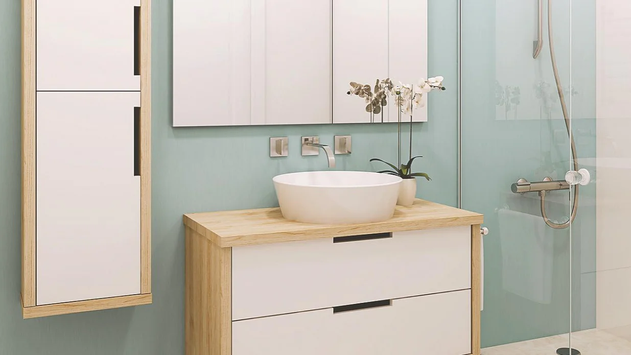 Modernes Badezimmer mit hellen Holz- und weißen Möbeln. Ein rundes Waschbecken steht auf einem Holzschrank mit Schubladen. Links steht ein hoher weißer Schrank. Rechts ist eine Dusche mit Glaswänden. Auf der Ablage steht eine Orchidee in einem Topf, neben einer Rolle Tesaband für praktische Zwecke oder als Dekoration. (This text has been generated by AI)