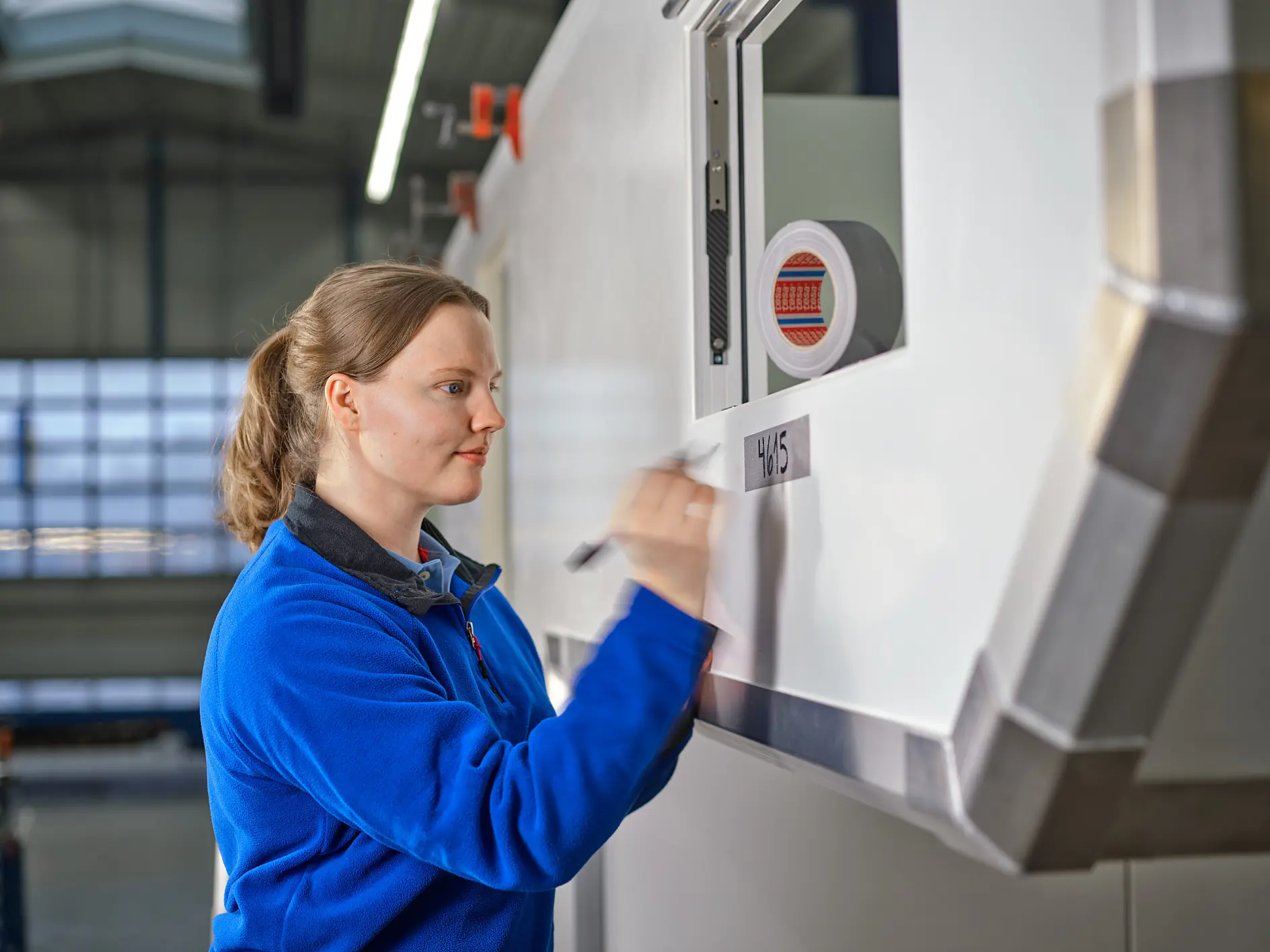 tesa worker in blue uniform operating control panel on large industrial machine in factory setting