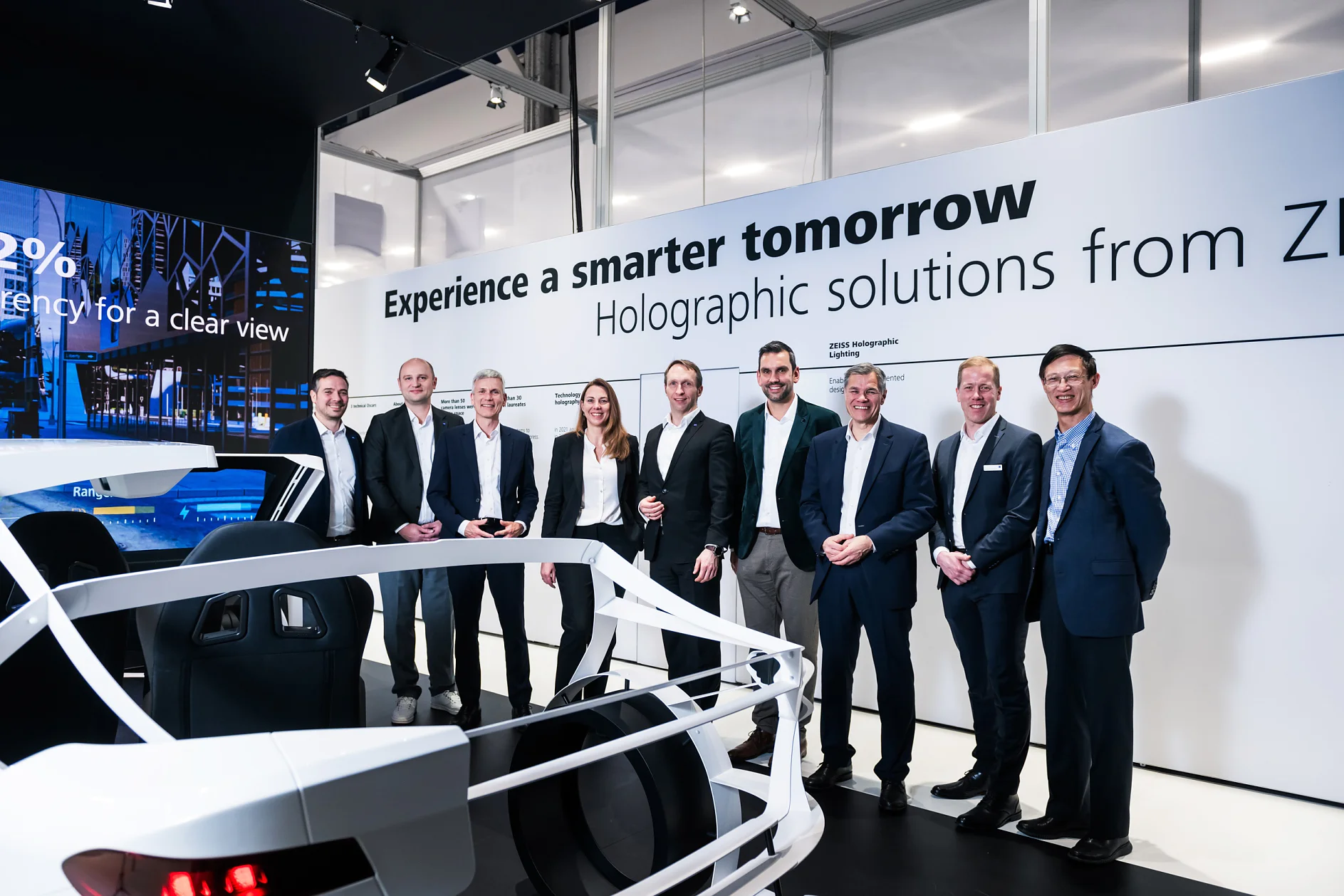 A group of business men and woman standing in front of a car on a fair