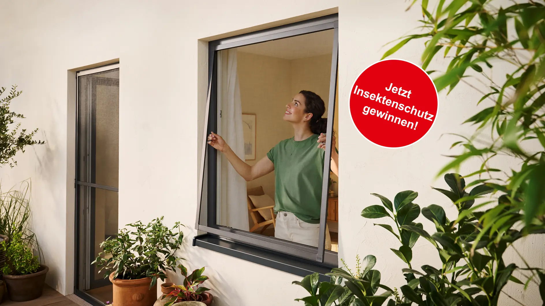 Eine Frau in einem grünen Hemd bringt in einem Raum mit Pflanzen einen Insektenschutz mit Tesafilm an einem Fenster an. Auf einem roten Schild steht "Jetzt Insektenschutz gewinnen!. (This text has been generated by AI)