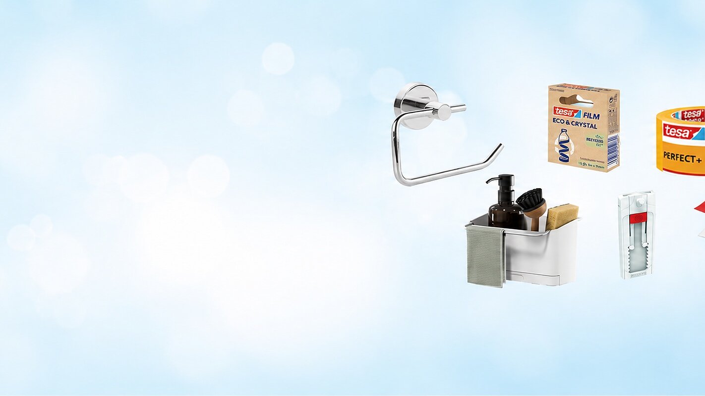 Verschiedene Haushaltsprodukte, darunter ein Toilettenpapierhalter, ein Seifenspenderset, eine Rolle Tesafilm, Klebehaken und Klebefolie auf blauem Hintergrund mit leichten Bokeh-Effekten. (This text has been generated by AI)