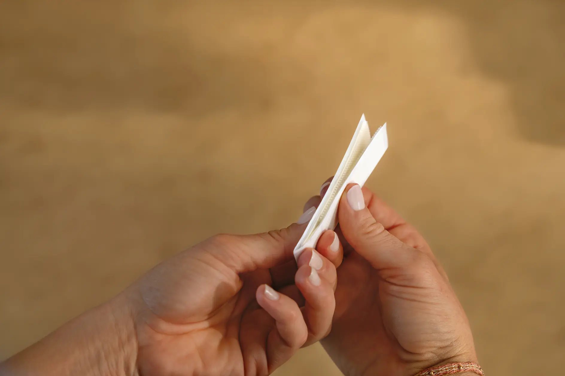 A pair of hands holding an unfolded white paper fortune teller against a blurred brown background. (This text has been generated by AI)