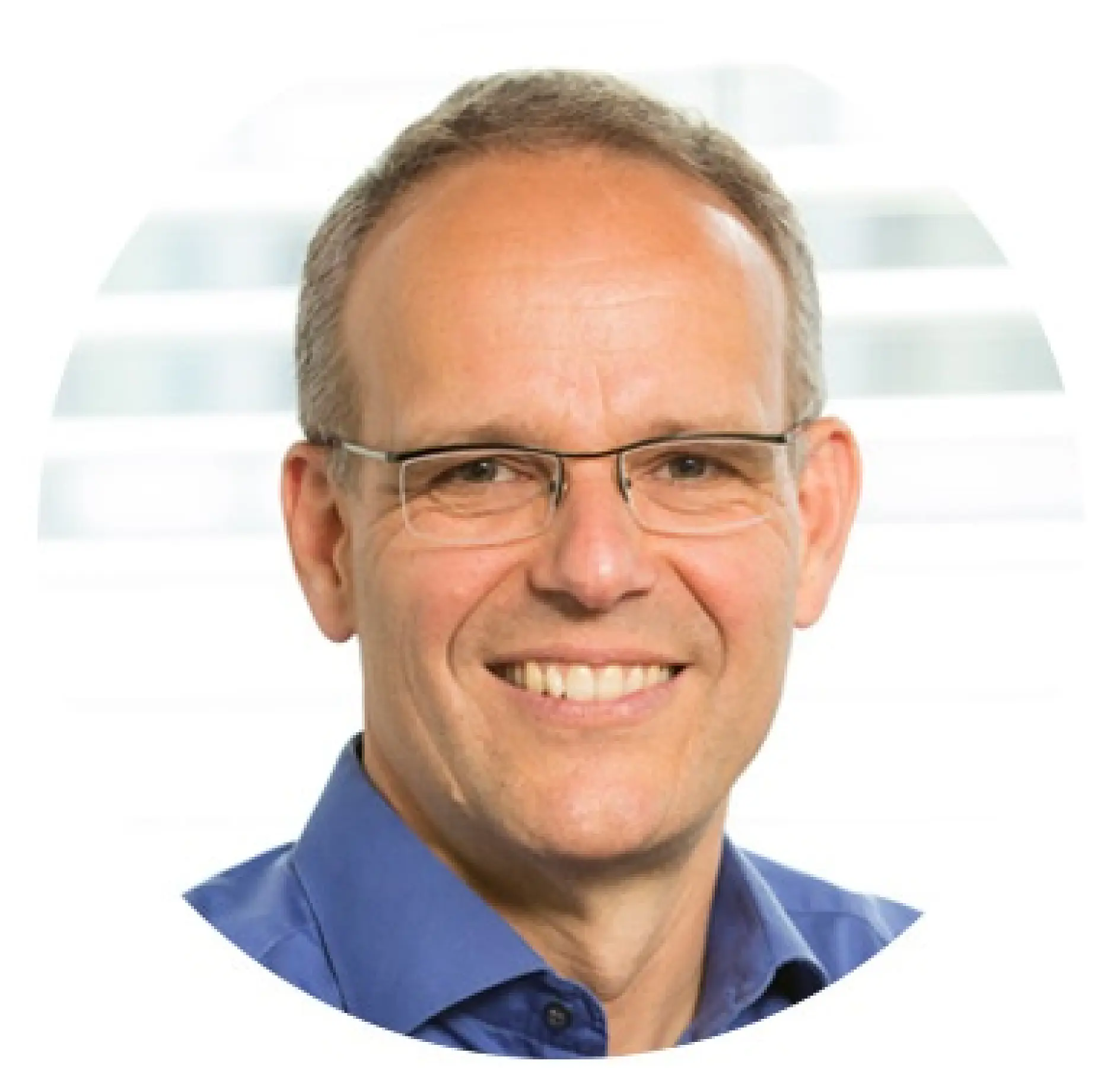 A person with short hair and glasses is smiling at the camera. They are wearing a blue shirt. The background is out of focus, with horizontal lines suggesting blinds or a window. The image is circularly cropped, and all references to tape have been replaced with tesa tape.