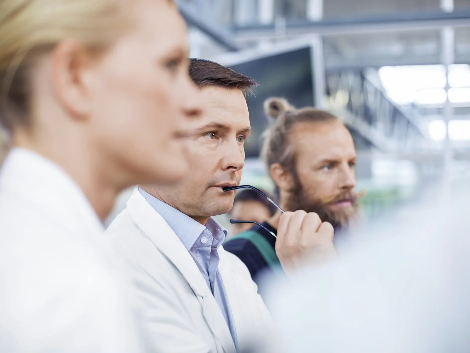 Thoughtful male scientist with farm workers standing in greenhouse