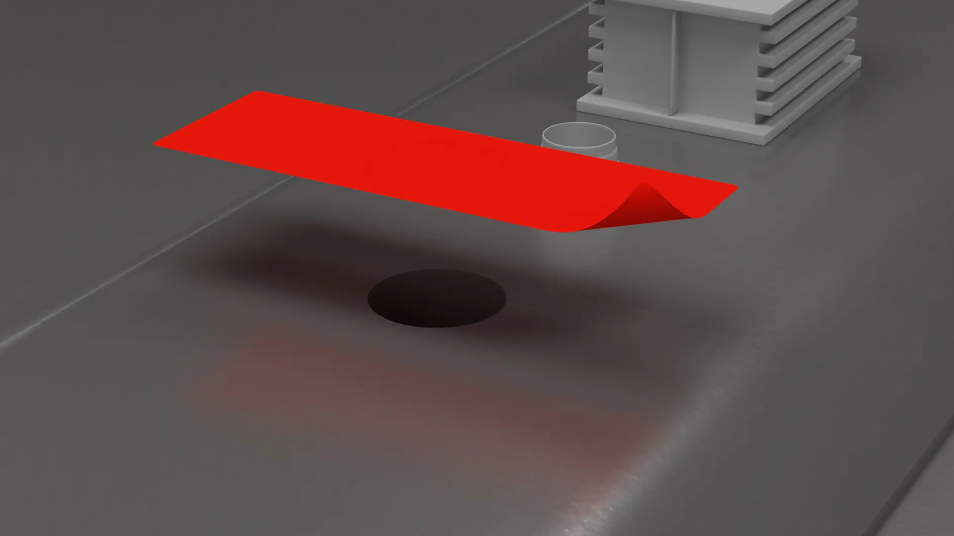 A glossy, red rectangular object hovers above a dark hole on a flat gray surface, next to a small white structure and a cylindrical component. The scene exudes tesa tapes mechanical and industrial feel. (This text has been generated by AI)