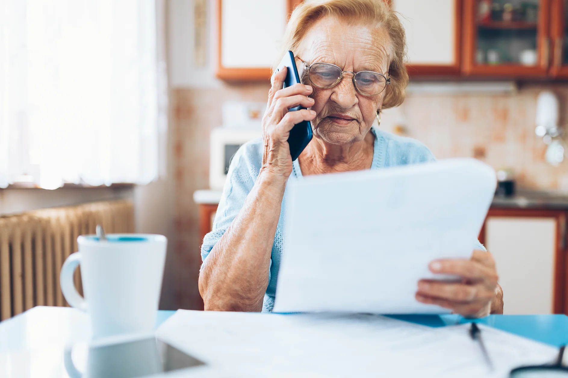 Elderly woman at home contacting custumer services after recieving a bill