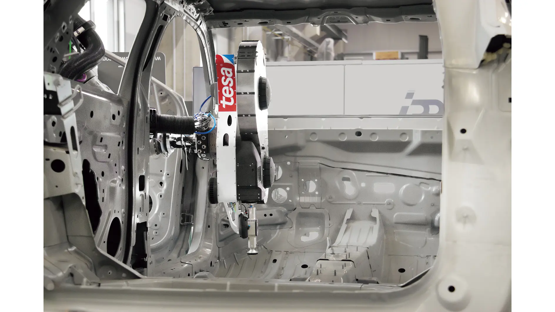 tesa robotic arm assembling the interior frame of a white car in an industrial manufacturing setting (This text has been generated by AI)