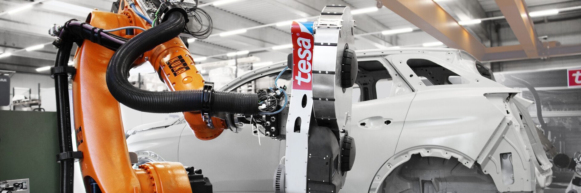 industrial robotic arm labeled tesa inspecting a white car body frame inside a modern automotive manufacturing facility