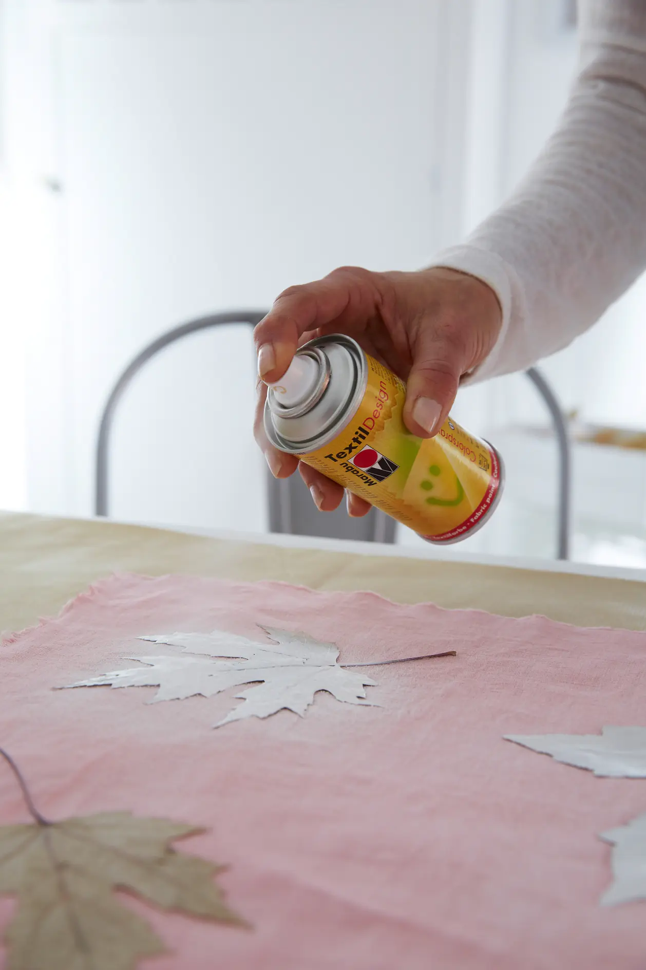 Spraying the fabric paint around the leaves.