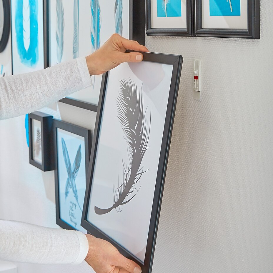 Hang the pictures step 05 Using tesa® adjustable adhesive nails for wallpaper & plaster to wall-mount a themed art collage wall.