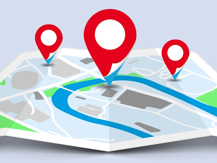 A stylized map with three red location pins. The map displays a blue river, gray buildings, and green spaces. The background is light blue, and the map is spread out across the image. (This text has been generated by AI)