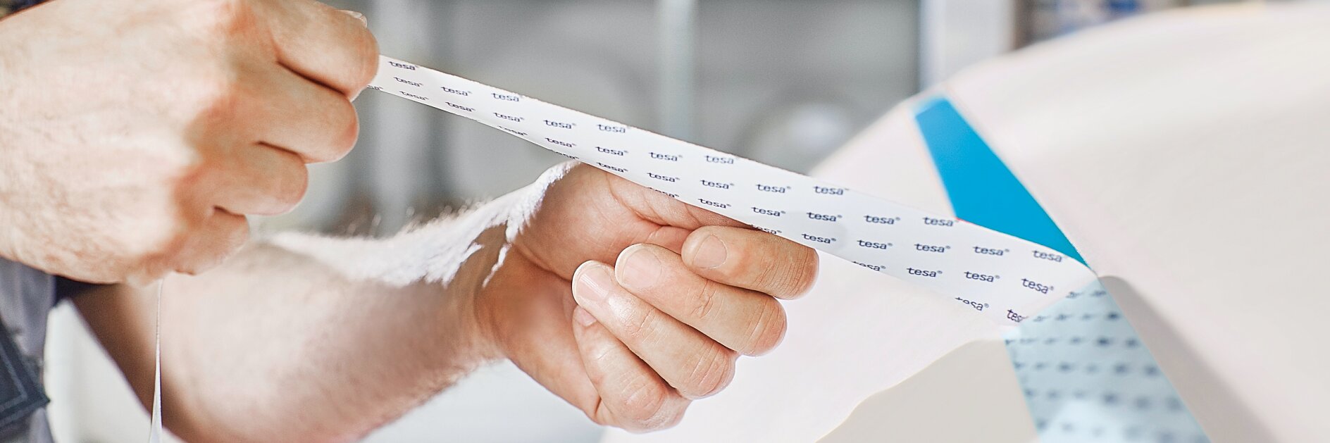 Person holding tesa EasySplice splicing tape, demonstrating how to use splicing tape for efficient and reliable web splicing in industrial processes