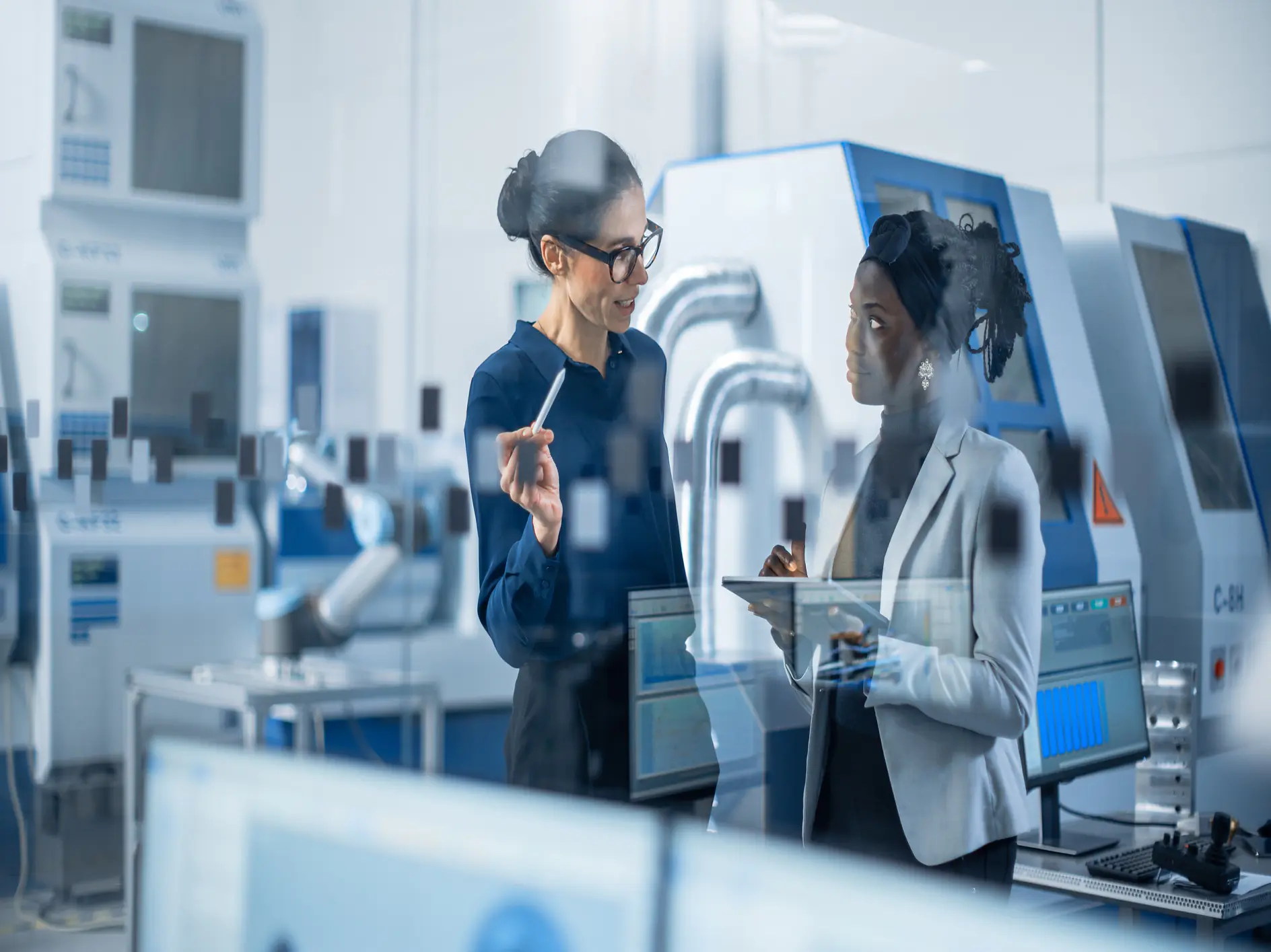 Two scientists in lab coats discuss data inside a modern laboratory with advanced equipment and machines. (This text has been generated by AI)