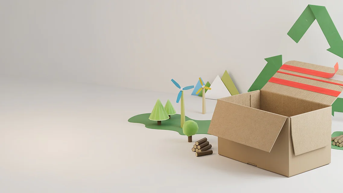 A cardboard box sits open on a white surface, sealed with tesa tape, with small models of trees, wind turbines, and logs behind it. A green recycling symbol is displayed on the wall in the background. (This text has been generated by AI)