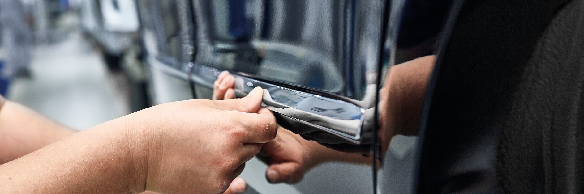 A hand attaching a part to a black car inside an indoor workshop seeting
