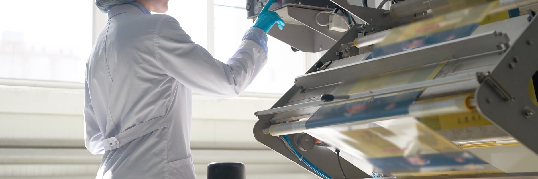 a woman operating a flexographic printing machine to print on film materials