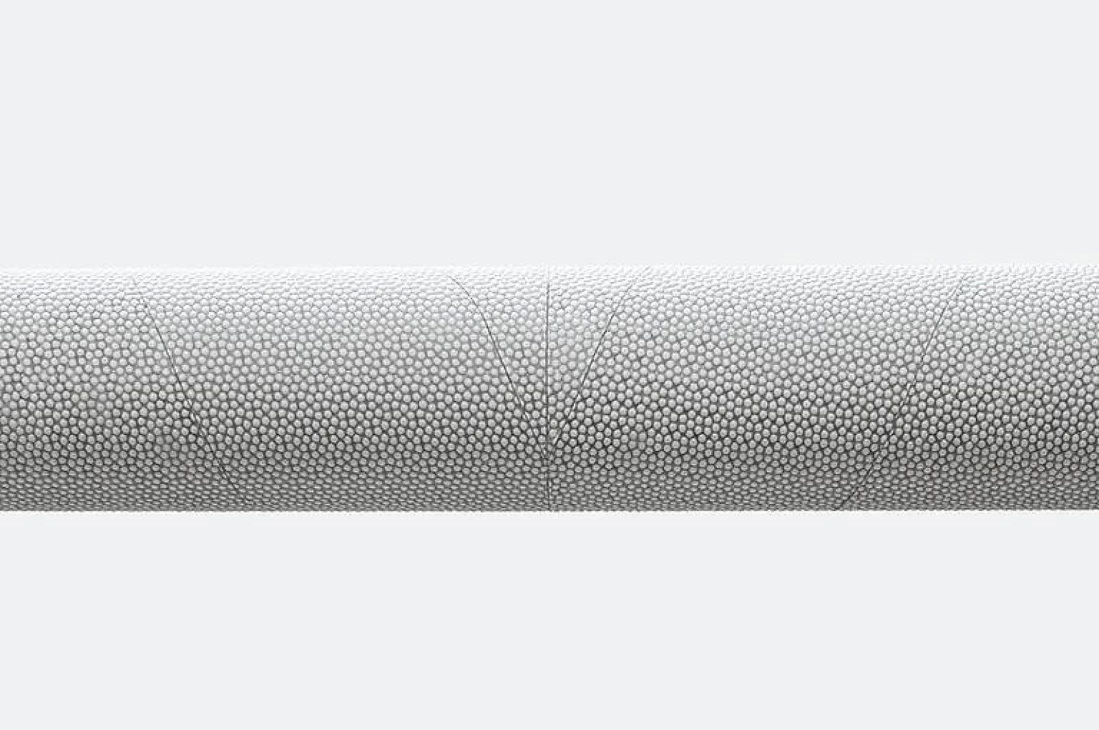 The object is a cylindrical item with a textured surface featuring numerous small, raised circular patterns. The background is a plain, light gray color, creating a contrast that highlights the intricate details of the object. The tesa tape extends horizontally across the frame. (This text has been generated by AI)