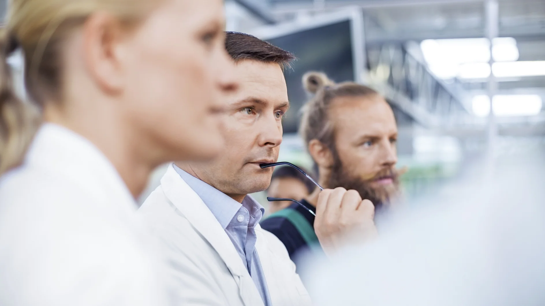Scientists Thoughtful male scientist with farm workers standing in greenhouse