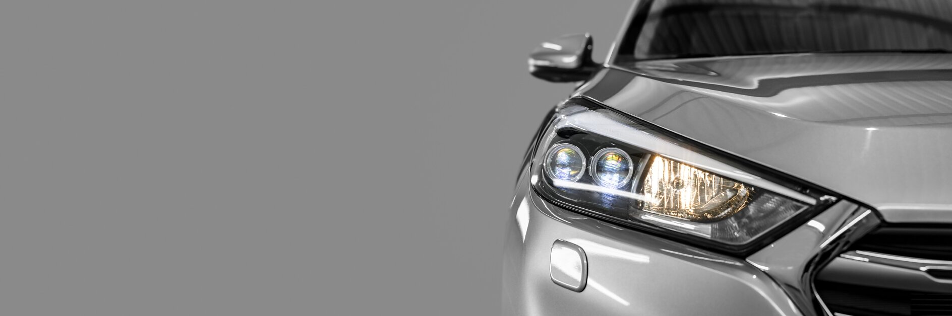 Gray modern car close-up on a black background, highlighting precision design and clean finish, supported by high-performance automotive tape.