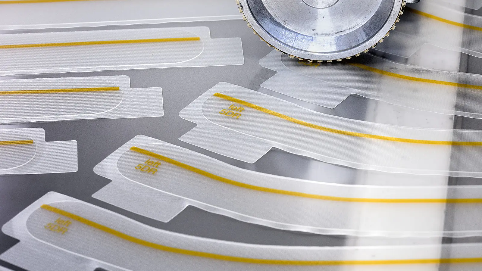 tesa adhesive strips arranged on a white surface next to a circular saw blade in an indoor workshop setting