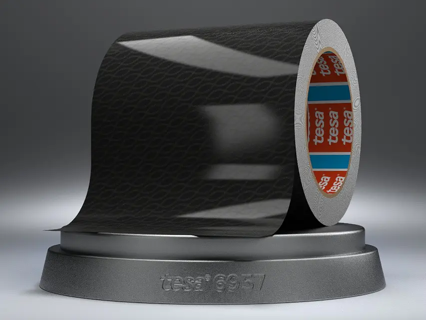 A partially unrolled roll of black tesa tape with a subtle pattern, resting on a gray circular stand. The inner part of the roll shows orange and blue detailing with text. The stand is labeled tesa 19657.