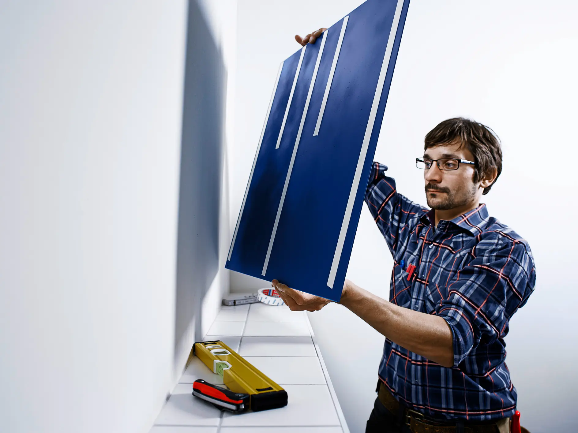 A man mounting a mirror on a wall using tesa’s removable mounting tape