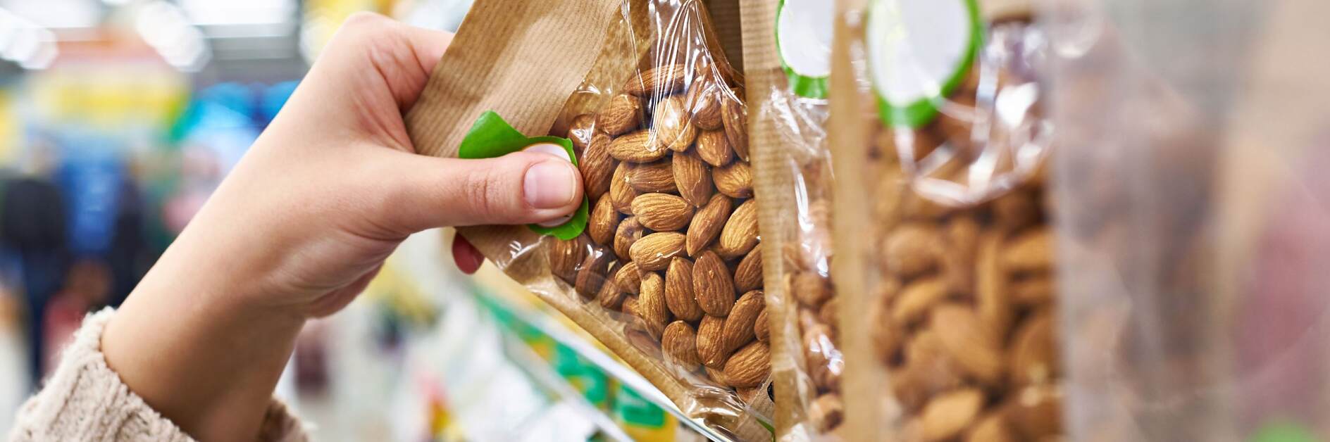 Hand with packaging of almond nuts in store