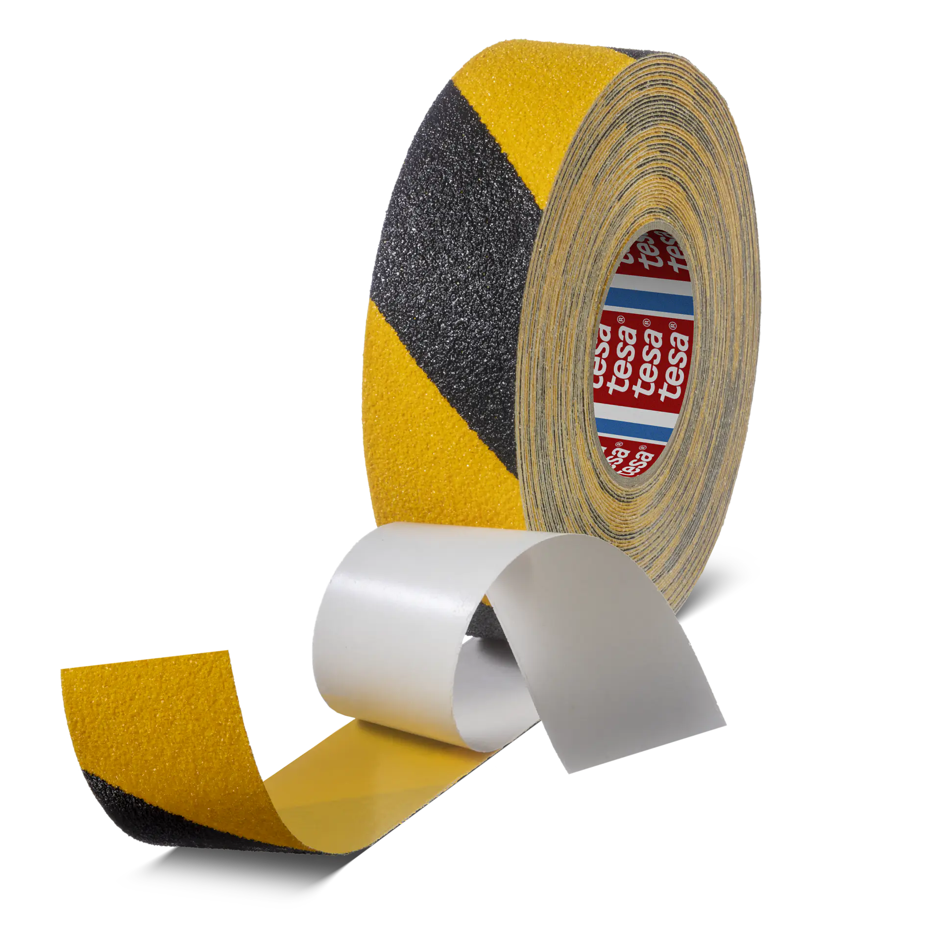 A roll of anti-slip tesa tape with yellow and black diagonal stripes is partially unrolled. The adhesive side is covered by a white backing. The brand name tesa is visible on the inner part of the roll.