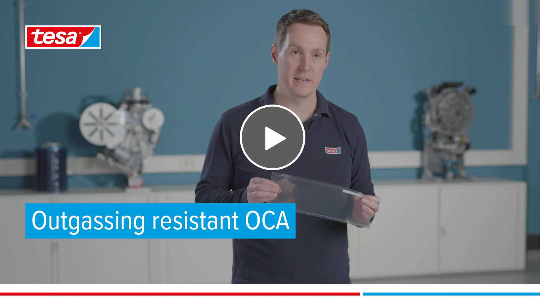 A person holding a transparent sheet stands in a room with industrial equipment in the background. The slide includes a play button overlay and the text Outgassing resistant OCA along with the tesa tape logo in the top left corner. (This text has been generated by AI)