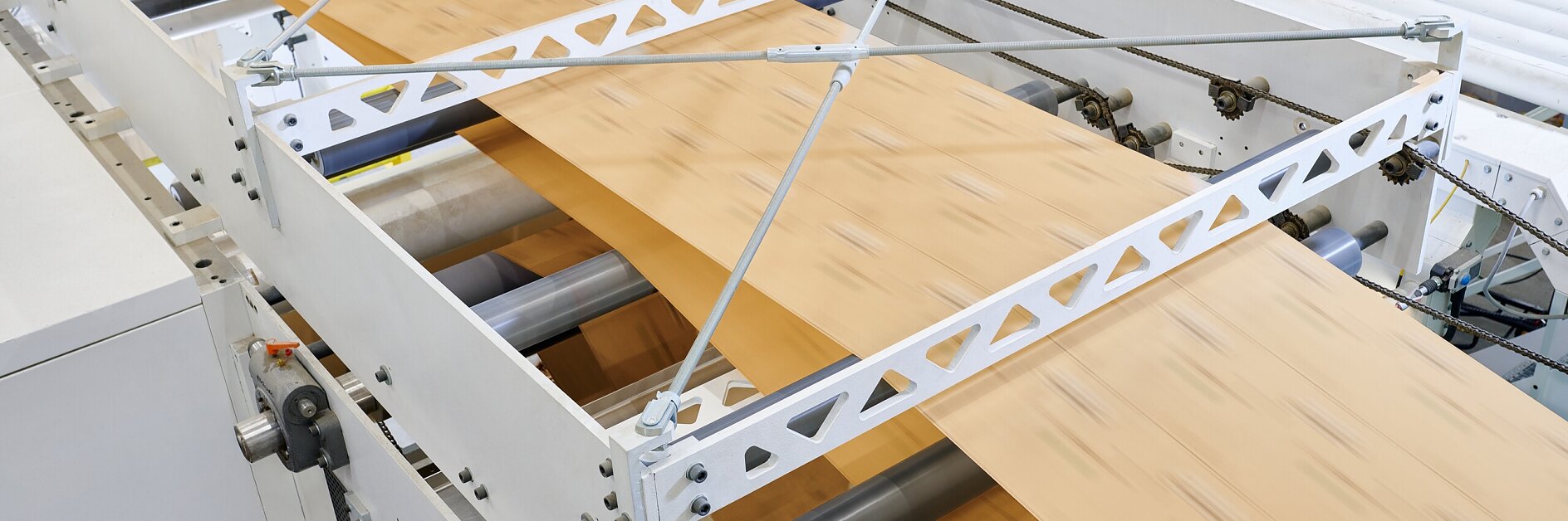 wooden boards moving on rollers under metal support beams inside an industrial facility for processing materials