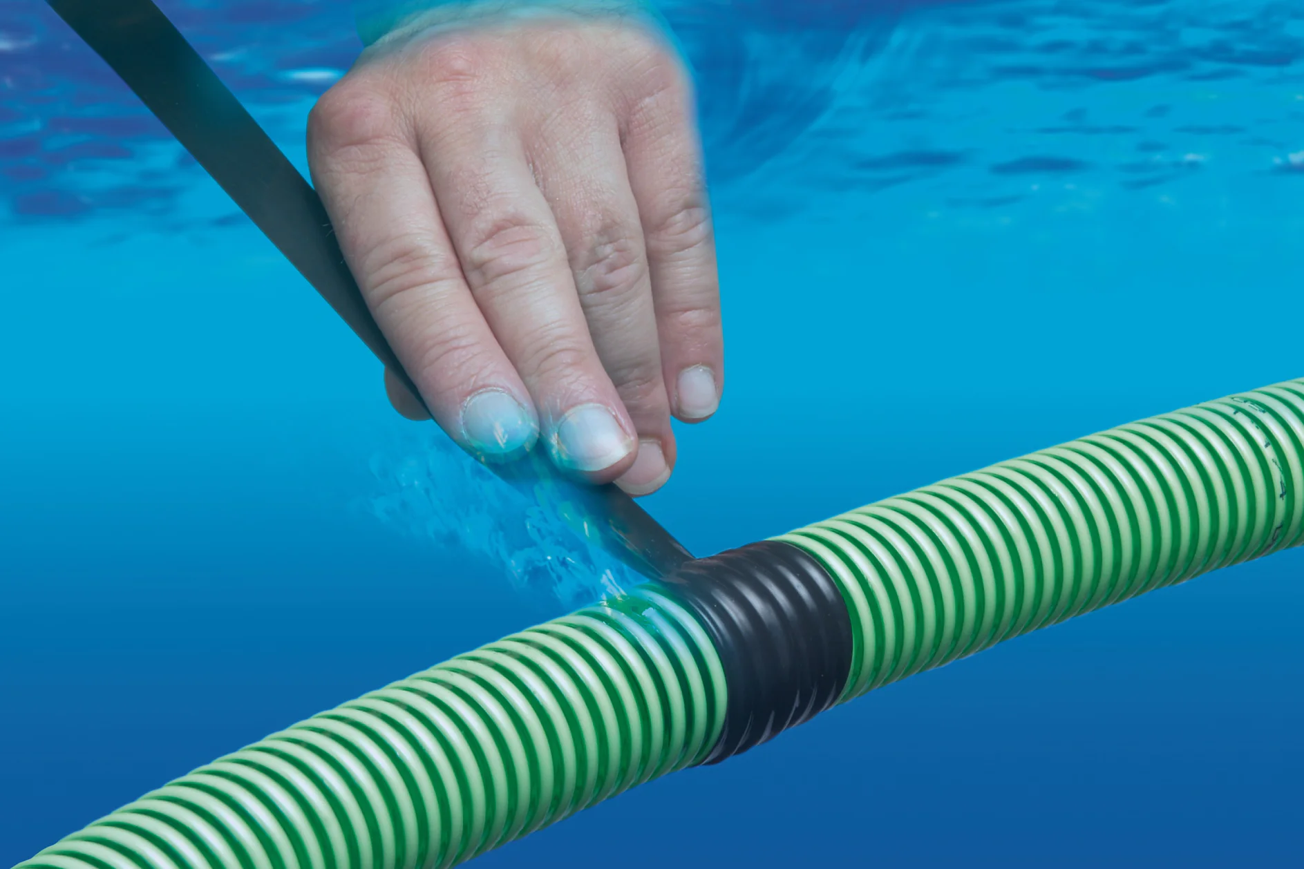 tesa_04600_ap_111_fullsize.jpg A hand is wrapping black tesa tape around a green and white striped hose underwater. The background is a gradient of blue, representing water. The hose appears to be submerged. (This text has been generated by AI)