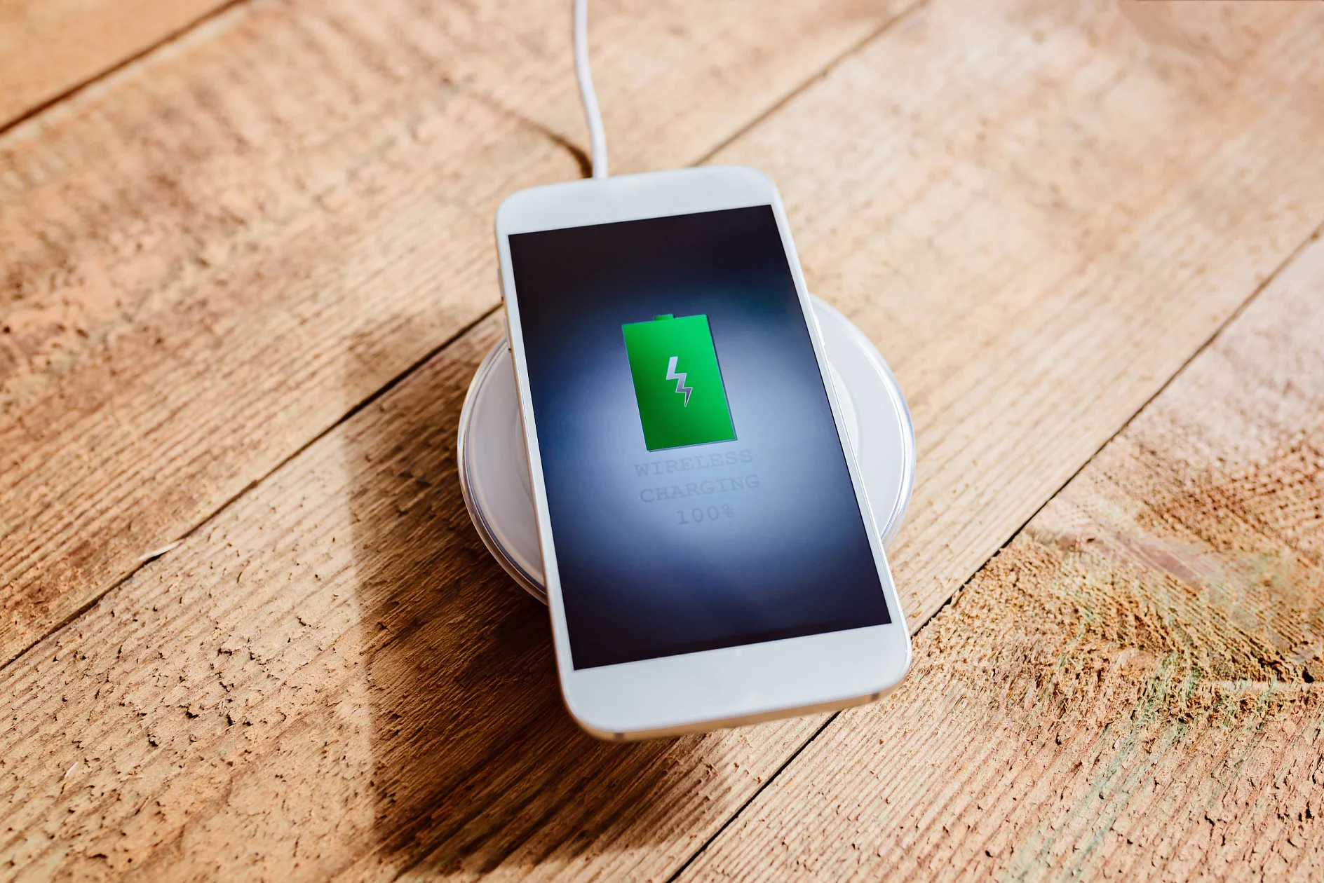 White smartphone charging on a charging pad.