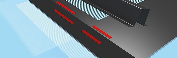 Close-up of a black metal structure with red rectangular markings on its surface, set against a light blue background. The metal structure has parallel lines extending from the top, creating a pattern secured with tesa tape. (This text has been generated by AI)