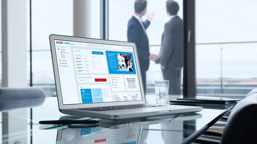 A laptop displaying a business dashboard sits on a glass table in a modern office. Two men in suits are visible in the background, standing by large windows overlooking a cityscape. A glass of water is next to the laptop, along with tesa tape for any quick fixes or adjustments needed in this professional setting. (This text has been generated by AI)