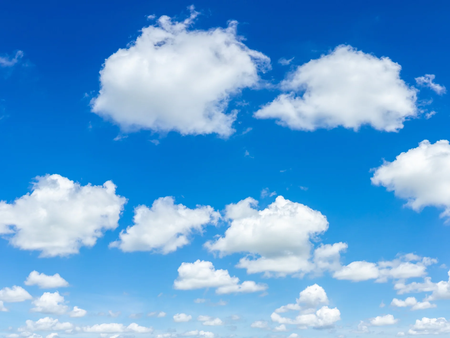 A clear blue sky features numerous fluffy white clouds of various sizes scattered across the scene. (This text has been generated by AI)
