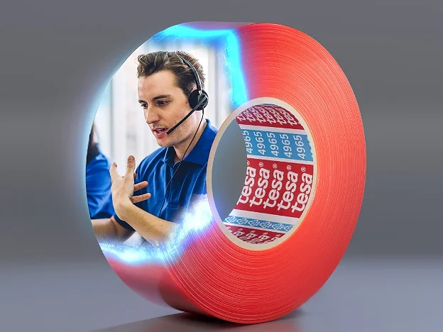 Tesa_Mounting_Overview_GetinTouch_624x468 A roll of red tesa tape with an image of a person wearing a headset, seemingly engaged in conversation, appearing inside the roll. The background is a plain gray gradient. (This text has been generated by AI)