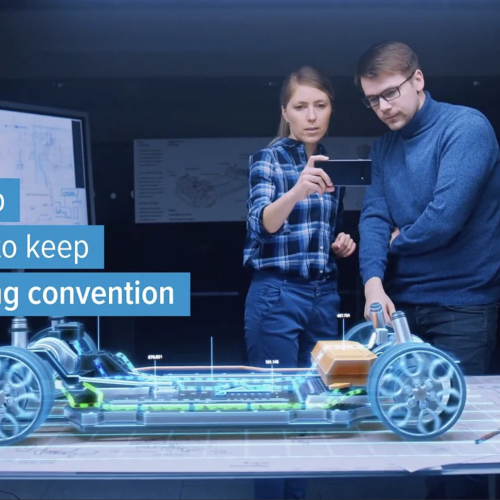 Two people stand by a table with a holographic car chassis projection. A woman holds a smartphone, and a man observes. A sign reads, To keep up you need to keep challenging convention. A tesa tape logo is in the top right corner. (This text has been generated by AI)