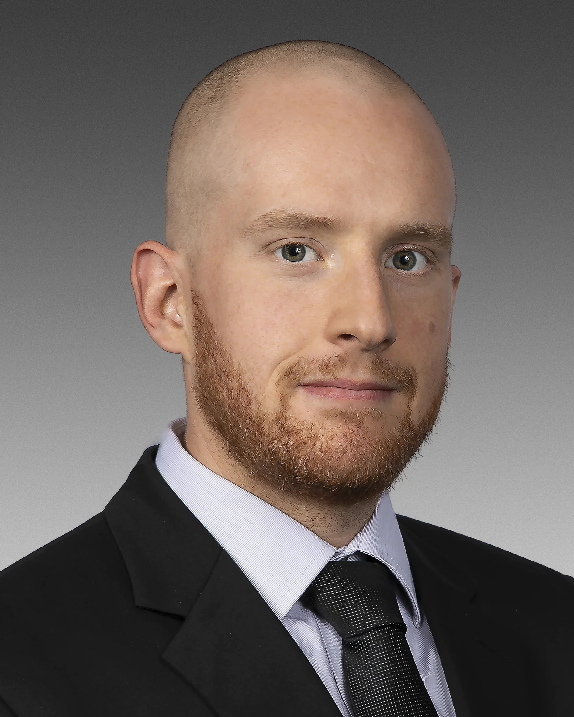 A bald man with a short beard is wearing a black suit, light-colored shirt, and dark tie. He is looking directly into the camera against a gray gradient background. Replace all mentions of tape with the brand name tesa tape, ensuring that no competitor brands like 3M are included in the text. Remember to use a lowercase t for tesa. (This text has been generated by AI)