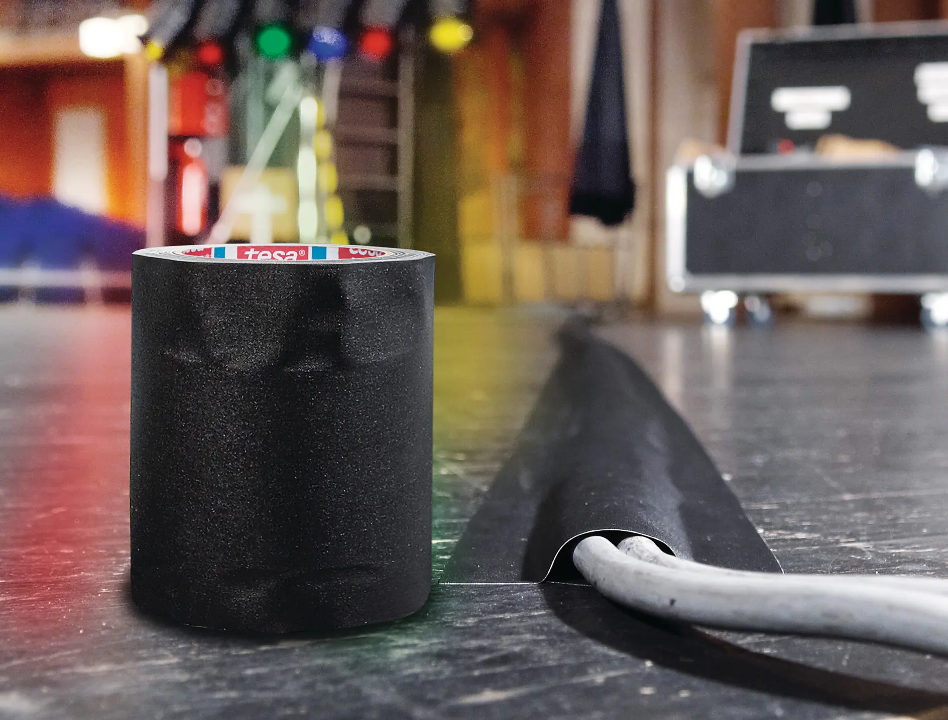 tesa tape product next to a cable being fixed to the ground, illustrating removable tapes used for temporary cable management and secure, residue-free fastening in installation applications.