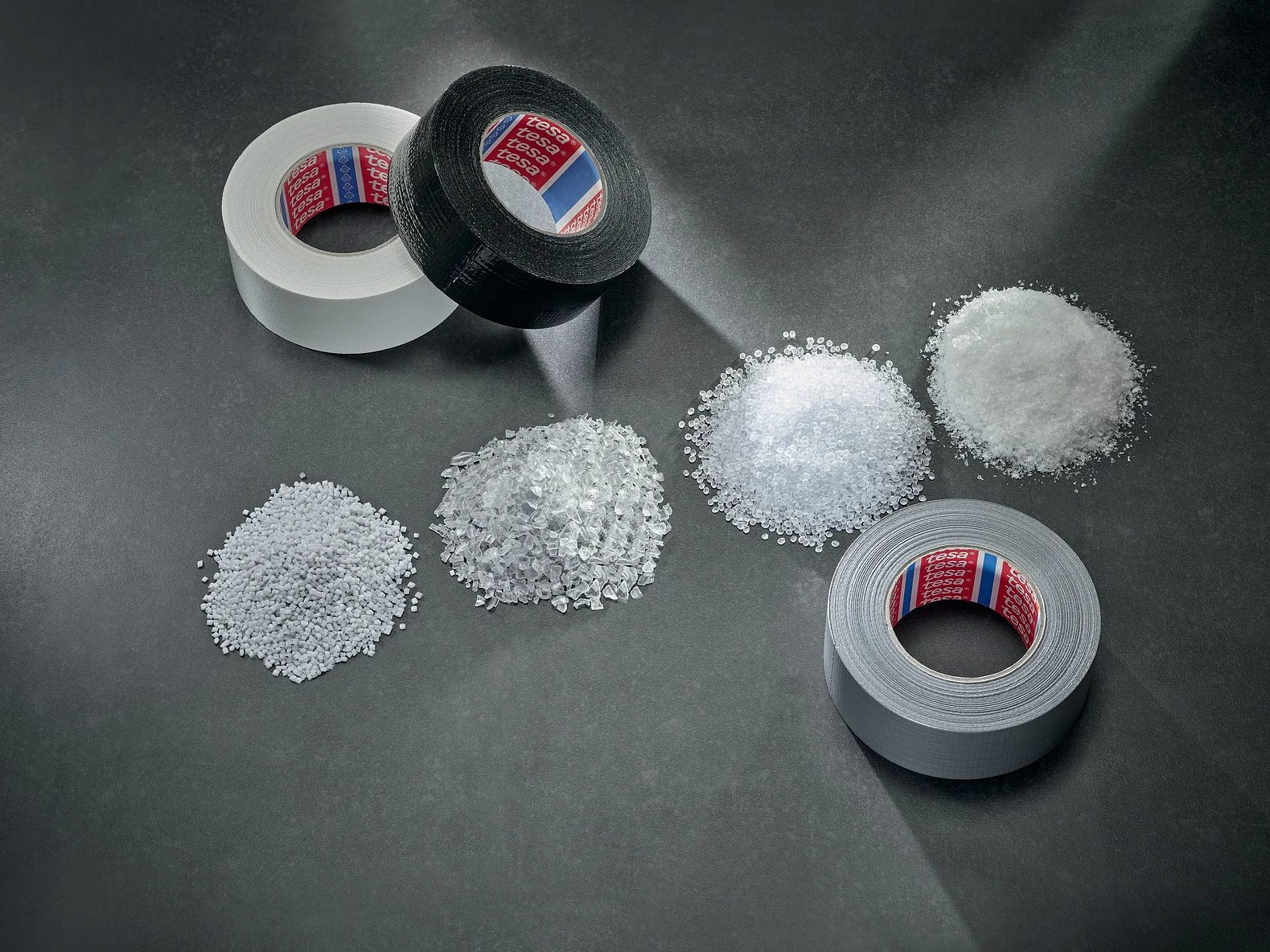 cloth-tape-2024-60462-duct-group-granulate-mood-01-Screen-Print tesa is switching to bio-based and recycled materials. Image shows three piles of plastics used in adhesives (This text has been generated by AI)