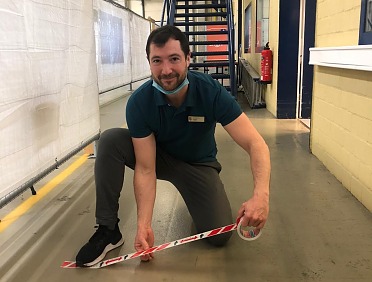 An employee of the vaccination center in Lüneburg, Germany applies the social distancing tape.