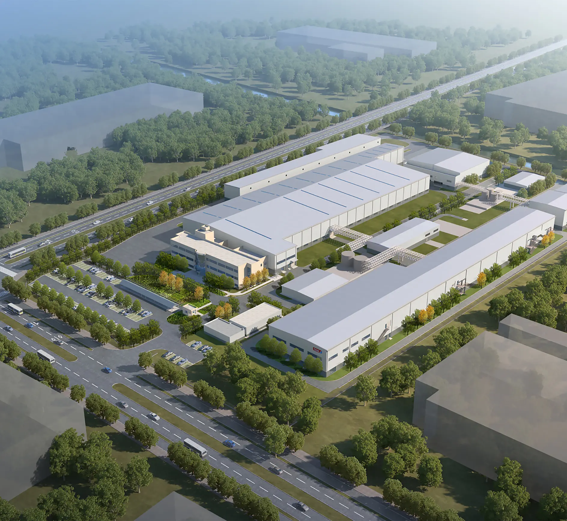Aerial view of a large industrial complex surrounded by trees and roads. The facility consists of multiple rectangular buildings with white roofs, parking areas, and landscaped greenery. Several surrounding roads are visible.